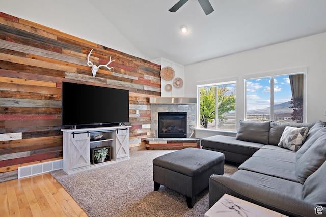 667 W Aspen Hills Blvd N, Saratoga Springs, UT 84045 - living area with lofted ceiling, wood walls, a glass covered fireplace, a ceiling fan, and wood-type flooring