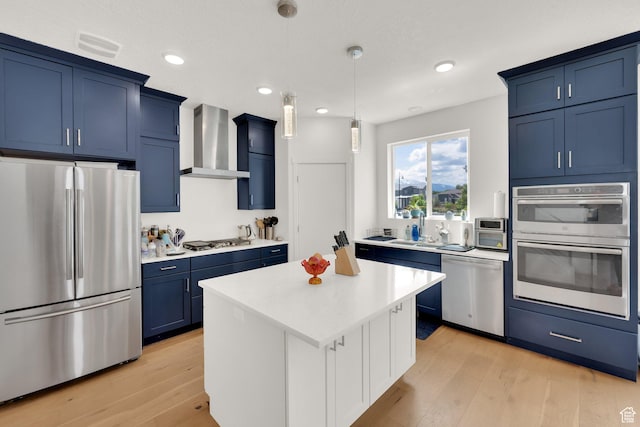 524 E Farmer Alumni Dr S, South Salt Lake, UT 84106 - kitchen featuring appliances with stainless steel finishes, wall chimney range hood, blue cabinetry, light countertops, and light wood finished floors