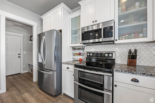 7886 N Bridleway Rd, Eagle Mountain, UT 84005 - kitchen with stainless steel appliances, white cabinetry, dark stone counters, decorative backsplash, and a textured ceiling