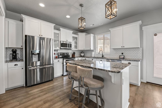 7886 N Bridleway Rd, Eagle Mountain, UT 84005 - kitchen featuring appliances with stainless steel finishes, white cabinetry, dark wood finished floors, recessed lighting, and backsplash