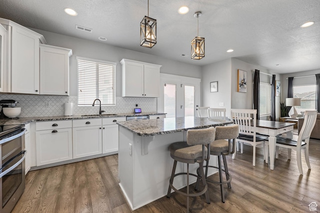 7886 N Bridleway Rd, Eagle Mountain, UT 84005 - kitchen featuring a sink, healthy amount of natural light, a kitchen island, light stone countertops, and recessed lighting