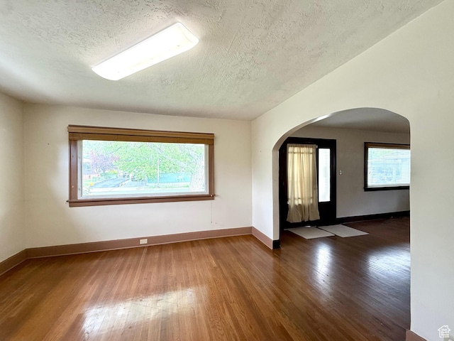 1980 S 600 E, Salt Lake City, UT 84105 - empty room with a textured ceiling, wood finished floors, plenty of natural light, baseboards, and arched walkways