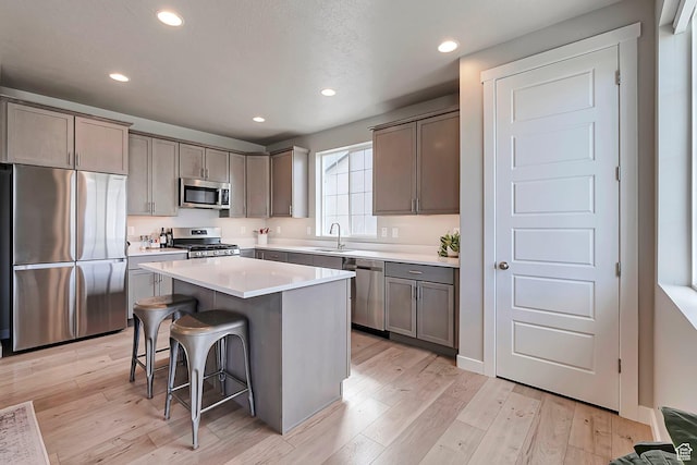 3864 W Safflower Dr, Lehi, UT 84043 - kitchen with appliances with stainless steel finishes, a sink, a kitchen bar, a center island, and light wood finished floors