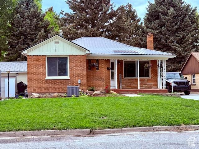 64 S 300 E, Preston, ID 83263 - view of front facade with covered porch, a front yard, a chimney, brick siding, and metal roof