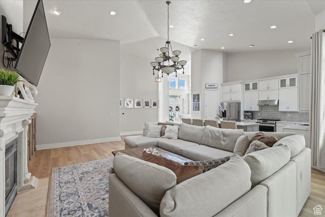 14771 S Brewster Dr, Draper, UT 84020 - living area with a fireplace with flush hearth, a chandelier, baseboards, high vaulted ceiling, and light wood-style floors