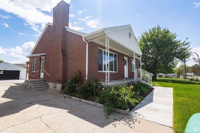 595 W Winchester St, Murray, UT 84123 - view of property exterior featuring brick siding, covered porch, a chimney, a yard, and an outdoor structure