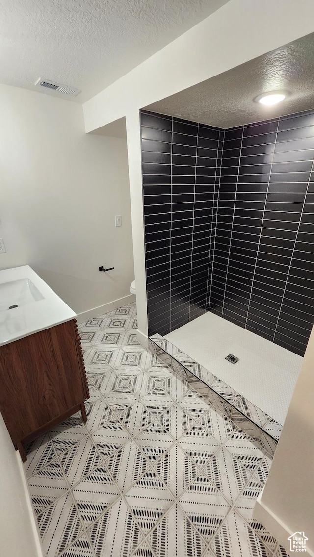 5757 S Surreyrun Rd, Murray, UT 84107 - full bathroom featuring a textured ceiling, a tile shower, baseboards, vanity, and toilet