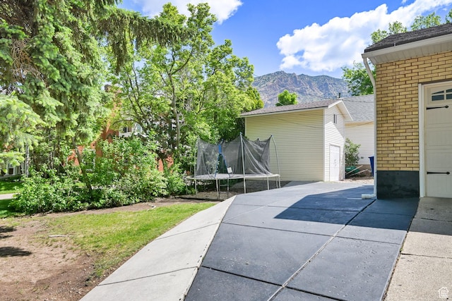 2890 Wheelock Ave, Ogden, UT 84403 - view of side of home with a trampoline, brick siding, a mountain view, and a patio area