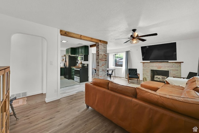 2890 Wheelock Ave, Ogden, UT 84403 - living area with a brick fireplace, a ceiling fan, light wood-style floors, a textured ceiling, and baseboards