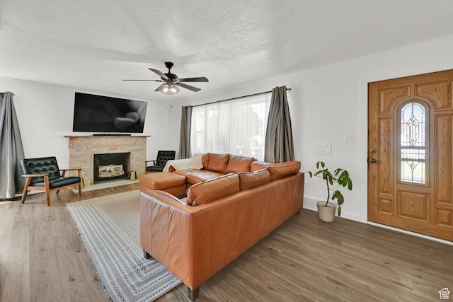 2890 Wheelock Ave, Ogden, UT 84403 - living area featuring a stone fireplace, wood finished floors, ceiling fan, and a textured ceiling