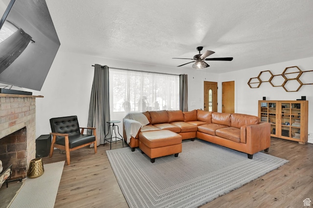2890 Wheelock Ave, Ogden, UT 84403 - living area featuring light wood-type flooring, a ceiling fan, a fireplace, and a textured ceiling