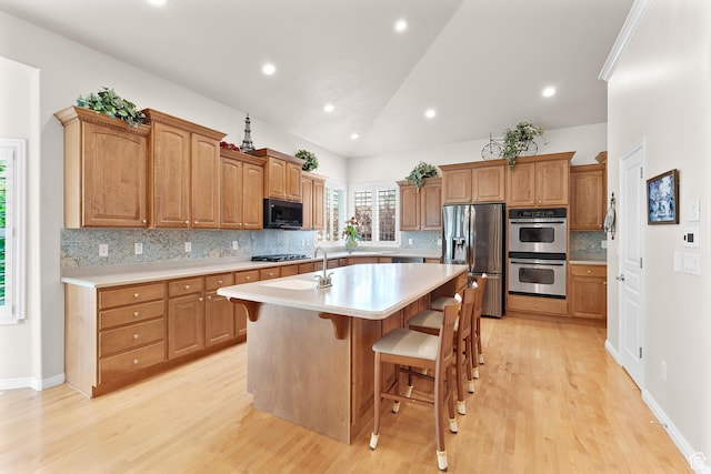 531 W Glendon Way, Pleasant Grove, UT 84062 - kitchen with stainless steel appliances, an island with sink, light countertops, light wood-style floors, and backsplash