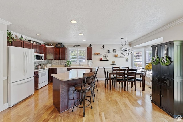 1516 N Willow Valley Dr W, Centerville, UT 84014 - kitchen featuring white appliances, a textured ceiling, light countertops, a kitchen breakfast bar, and light wood finished floors