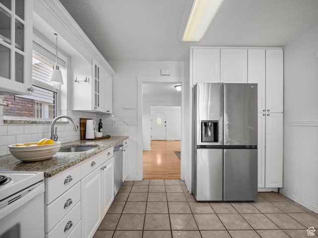 1067 S 400 E, Salt Lake City, UT 84111 - kitchen featuring appliances with stainless steel finishes, white cabinetry, backsplash, and light tile patterned floors