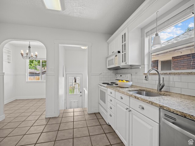 1067 S 400 E, Salt Lake City, UT 84111 - kitchen with white appliances, light tile patterned floors, a chandelier, white cabinetry, and decorative backsplash