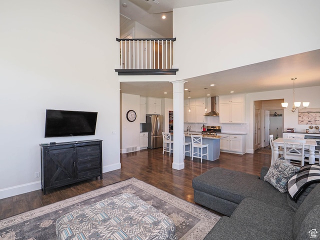 104 S Summer Breeze Ln W, Layton, UT 84041 - living area with baseboards, dark wood-type flooring, a chandelier, a towering ceiling, and ornate columns