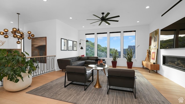 14708 S Woods Landing Ct E, Draper, UT 84020 - living room with light wood-style floors, recessed lighting, ceiling fan, a glass covered fireplace, and a chandelier