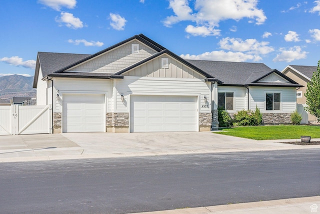 4957 N Sage Dr, Eagle Mountain, UT 84005 - view of front facade with a garage, stone siding, driveway, a gate, and a mountain view