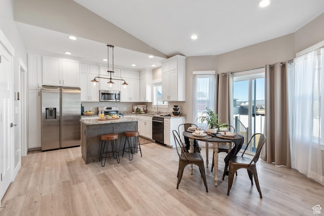 4957 N Sage Dr, Eagle Mountain, UT 84005 - kitchen featuring appliances with stainless steel finishes, a kitchen island, white cabinets, vaulted ceiling, and a kitchen breakfast bar