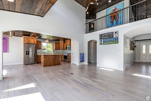 3824 N Patiosprings Dr, Eden, UT 84310 - unfurnished living room with arched walkways, wood ceiling, light wood finished floors, healthy amount of natural light, and a towering ceiling