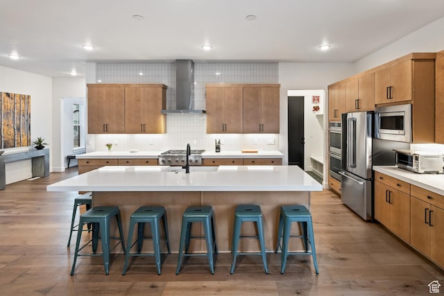 6592 Purple Poppy Ln Unit 117, Park City, UT 84098 - kitchen with wall chimney exhaust hood, appliances with stainless steel finishes, a breakfast bar, light countertops, and recessed lighting