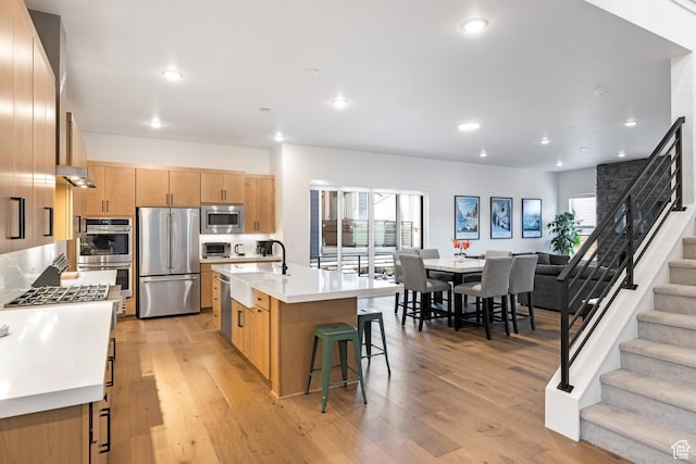 6592 Purple Poppy Ln Unit 117, Park City, UT 84098 - kitchen featuring appliances with stainless steel finishes, open floor plan, a kitchen breakfast bar, light countertops, and light wood-style flooring