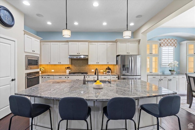 10451 S Abbott Way S, Jordan, UT 84009 - kitchen with stainless steel appliances, a sink, under cabinet range hood, a center island with sink, and decorative backsplash