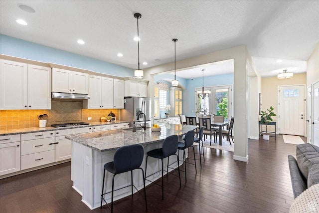 10451 S Abbott Way S, Jordan, UT 84009 - kitchen with appliances with stainless steel finishes, a kitchen bar, tasteful backsplash, a sink, and a kitchen island with sink