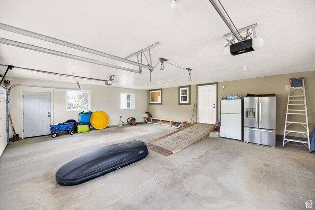 304 N 1000 E, Hyde Park, UT 84318 - garage with freestanding refrigerator, stainless steel fridge with ice dispenser, and a garage door opener