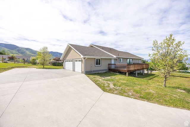 304 N 1000 E, Hyde Park, UT 84318 - view of side of property featuring a lawn, concrete driveway, a deck with mountain view, a garage, and stucco siding