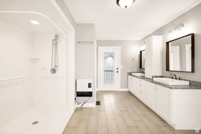 304 N 1000 E, Hyde Park, UT 84318 - bathroom featuring heating unit, wood finished floors, a shower, double vanity, and baseboards