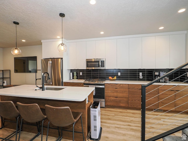 423 E 2100 S Unit 204, Salt Lake City, UT 84115 - kitchen with appliances with stainless steel finishes, light wood finished floors, white cabinets, recessed lighting, and backsplash