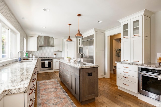 2262 E 1700 S, Salt Lake City, UT 84108 - kitchen with built in appliances, wall chimney exhaust hood, hardwood / wood-style floors, a sink, and light stone counters