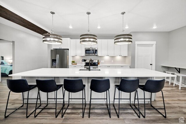 670 N Lake Sight Dr, Garden City, UT 84028 - kitchen with stainless steel appliances, a large island with sink, recessed lighting, light wood-style floors, and white cabinetry