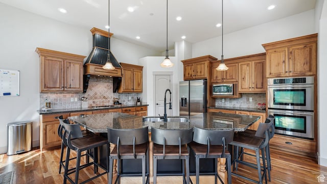 740 S Oak Dr, Woodland Hills, UT 84653 - kitchen with stainless steel appliances, a sink, backsplash, a center island with sink, and brown cabinetry