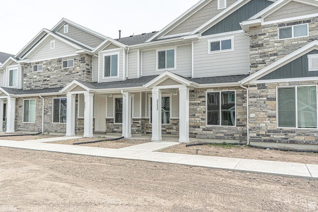 2205 S 1120 W Unit 62, Nibley, UT 84321 - view of front of house featuring board and batten siding, stone siding, a porch, and roof with shingles