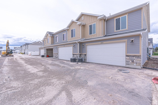 2205 S 1120 W Unit 62, Nibley, UT 84321 - view of front of house featuring stone siding, board and batten siding, central air condition unit, and an attached garage