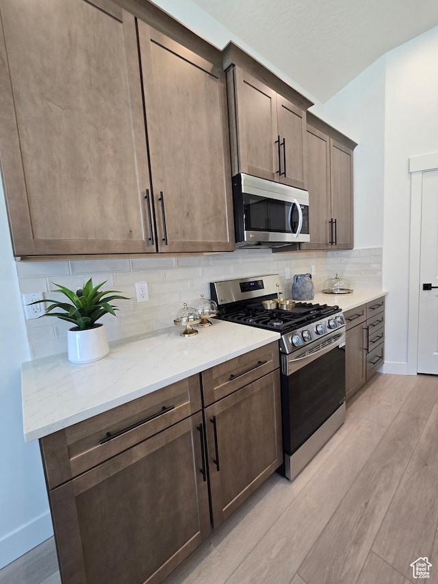 3564 W Haven Hollow Dr S, South Jordan, UT 84095 - kitchen featuring appliances with stainless steel finishes, light wood-style floors, tasteful backsplash, light stone countertops, and baseboards
