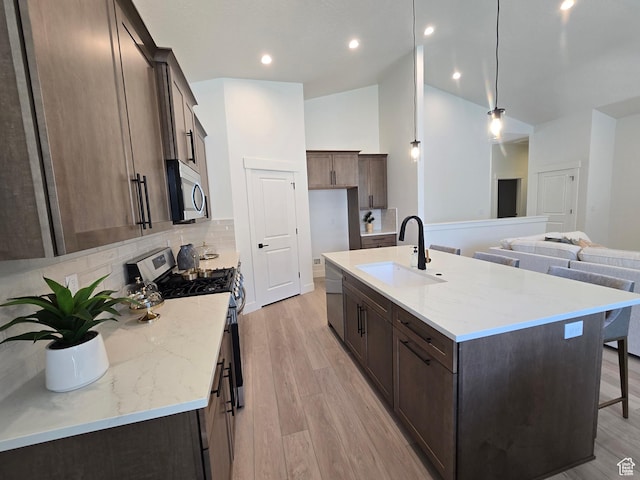 3564 W Haven Hollow Dr S, South Jordan, UT 84095 - kitchen featuring appliances with stainless steel finishes, a sink, decorative backsplash, a kitchen island with sink, and light wood-type flooring