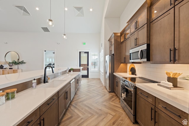 3564 W Haven Hollow Dr S, South Jordan, UT 84095 - kitchen with appliances with stainless steel finishes, a sink, high vaulted ceiling, hanging light fixtures, and glass insert cabinets