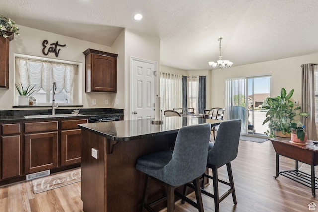 1044 S 1775 W, Syracuse, UT 84075 - kitchen featuring a breakfast bar, a sink, dark countertops, a chandelier, and light wood-style floors
