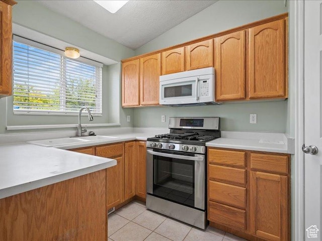 2014 S Jenny Ln, Clearfield, UT 84015 - kitchen featuring stainless steel gas range, white microwave, light tile patterned flooring, light countertops, and lofted ceiling