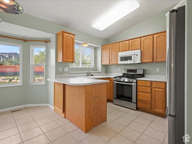 2014 S Jenny Ln, Clearfield, UT 84015 - kitchen featuring appliances with stainless steel finishes, a peninsula, light tile patterned floors, lofted ceiling, and light countertops