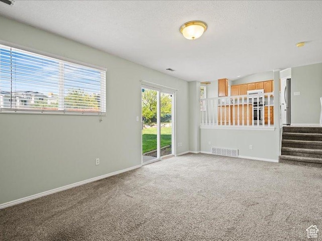 2014 S Jenny Ln, Clearfield, UT 84015 - unfurnished living room with light carpet, baseboards, stairs, and a textured ceiling