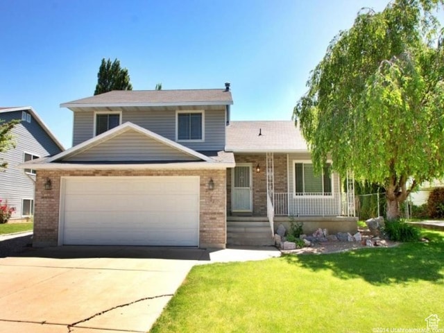 2182 N 850 W, Clinton, UT 84015 - tri-level home featuring brick siding, a porch, a front yard, concrete driveway, and an attached garage