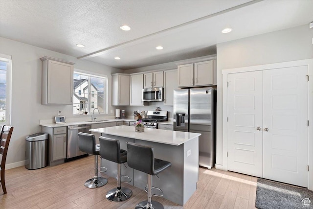 2221 W Prevedel Dr S, West Haven, UT 84401 - kitchen with stainless steel appliances, gray cabinetry, light wood-style floors, a sink, and a kitchen breakfast bar