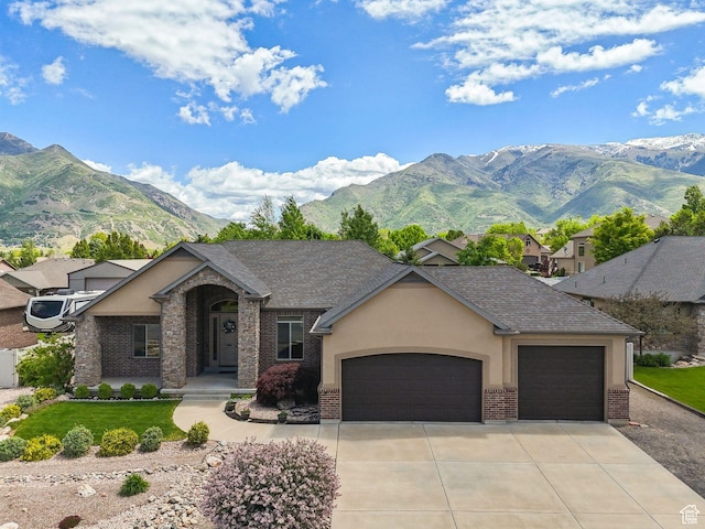 7538 S 1740 E, South Weber, UT 84405 - view of front facade with a garage, brick siding, driveway, a mountain view, and a front yard