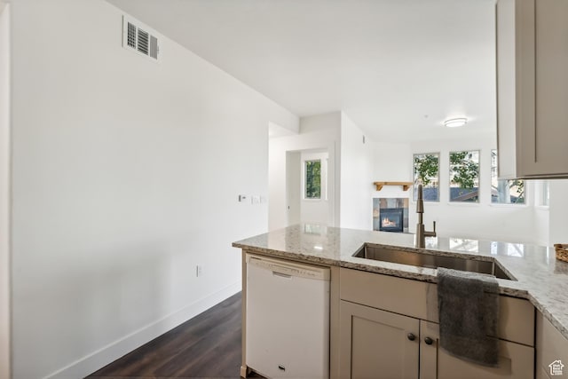 6749 N 2200 W Unit B102, Park City, UT 84098 - kitchen featuring white dishwasher, a sink, a tile fireplace, light stone counters, and dark wood-type flooring