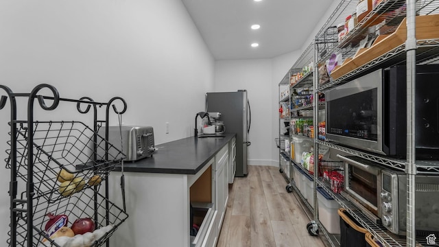 5557 W 13680 S, Herriman, UT 84096 - kitchen with dark countertops, recessed lighting, light wood finished floors, freestanding refrigerator, and baseboards
