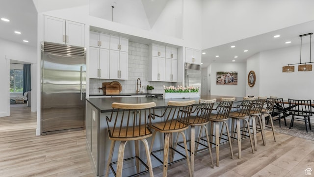 5557 W 13680 S, Herriman, UT 84096 - kitchen with built in fridge, light wood-style flooring, white cabinets, a spacious island, and recessed lighting
